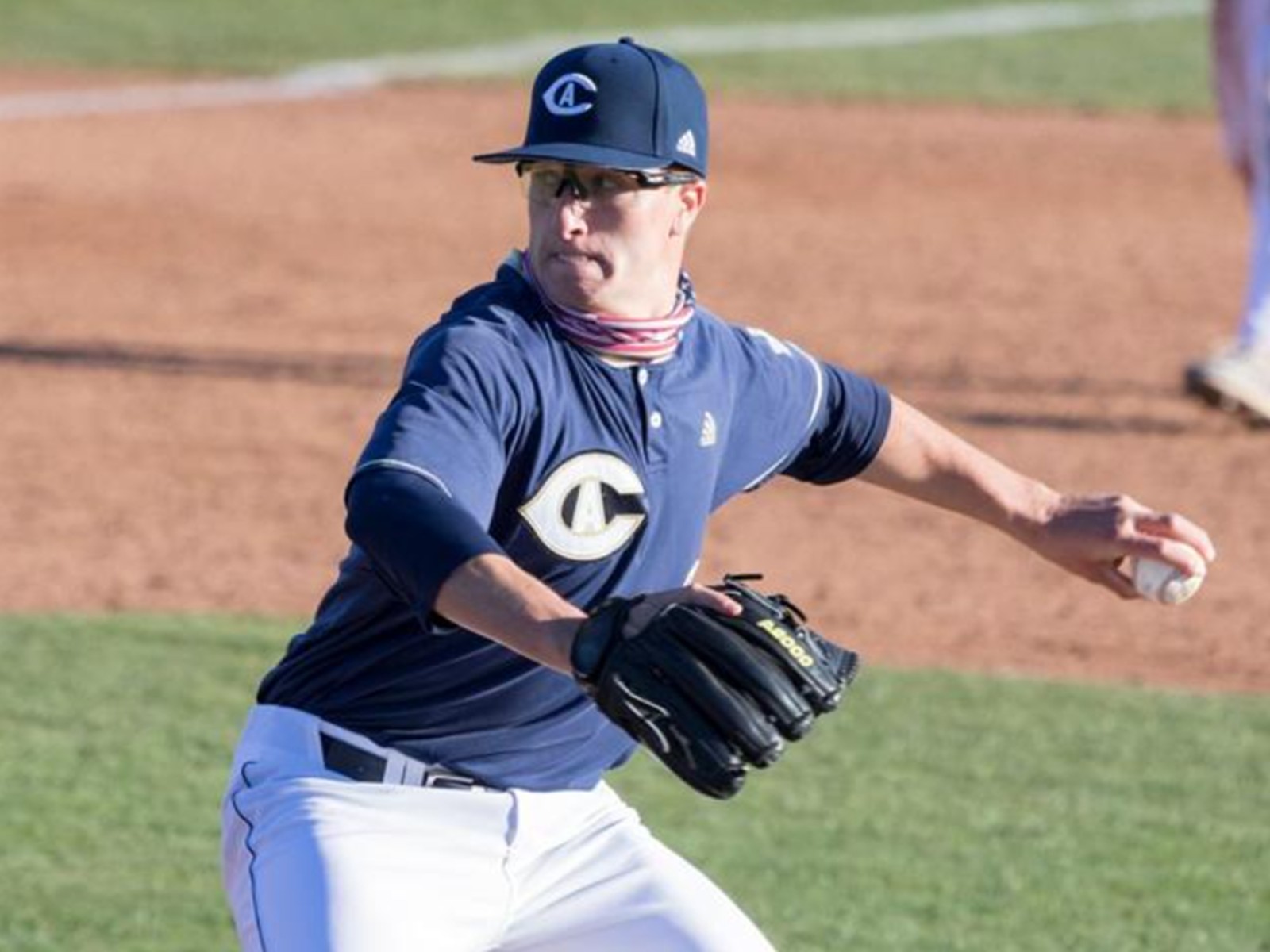 Mid-delivery on the mound during a college game